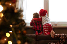 Children Look Out Of The Window On Christmas