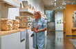 © JENOCHE - Woman visitor in historical museum looking at art object.