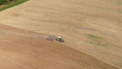 Wall Mural - aerial view of a tractor plowing a dry field in the summer - preparation for the new harvest