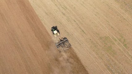 Wall Mural -  aerial view of a tractor plowing a dry agricultural field in the summer - preparation for the new harvest - top view