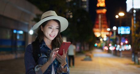 Wall Mural - Travel Woman use of mobile phone look for the location in Tokyo city at night