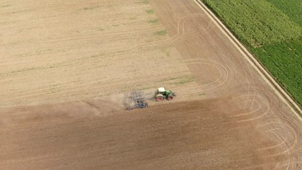 Wall Mural - aerial view of a tractor plowing a dry field in the summer - preparation for the new harvest