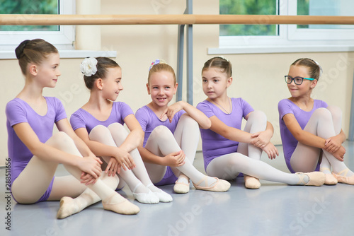 Five young ballerinas sitting on the floor. Cute little ballet dancers in purple leotards having a rest. Beautiful and talented girls. Stock Photo | Adobe Stock