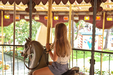 Wall Mural - Castelnuovo del Garda, Italy - August 13 2019: Happy girl riding on carousel horse. Gardaland Theme Park in Castelnuovo Del Garda, Verona, Italy.