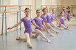 © DenisProduction.com - Young ballerinas stretching on the floor. Group of young ballet dancers sitting on the floor and practicing stretching at choreography lesson.