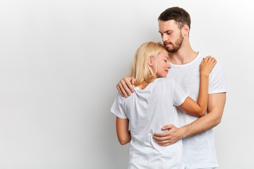 Supportive guy hugs and tries to appease his girlfriend who has desperate look, girl has problems, isolated white background, studio shot, copy space. love, negative feeling and emotion,lifestyle