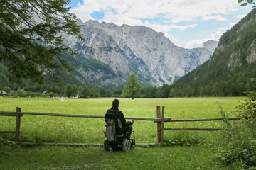 Wall Mural - Happy man on wheelchair in nature. Exploring forest wilderness on an accessible dirt path.