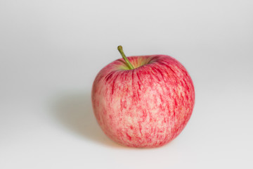 Wall Mural - One apple on white background. Red juicy ripe apple close up. Fresh striped fruit. Side view