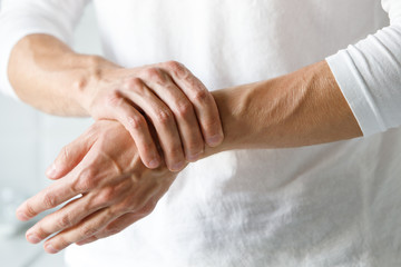 closeup of male arms holding her painful wrist caused by prolonged work on the computer, laptop. car