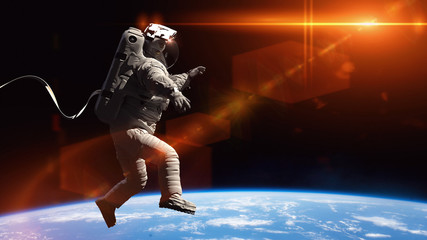 Wall Mural - astronaut performing a space walk in orbit of the blue planet earth