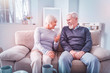 © zinkevych - Couple of beaming retired man and woman sitting on sofa and chatting