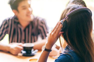 Poster - Closeup image of friends enjoyed talking, listening to music with headphone and drinking coffee together in cafe