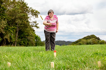 Wall Mural - Geistig behinderte Frau spielt auf einer Wiese Kubb, Geschicklichkeit und Konzentration