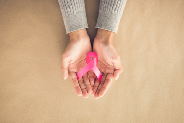 Wall Mural - Woman hands giving satin pink ribbon, supporting symbol of breast cancer awareness campaign in October