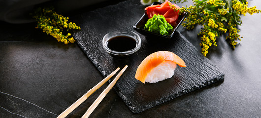 Canvas Print - Delicious seafood, sushi with salmon closeup. Traditional japanese cuisine restaurant menu item. Oriental culinary, eastern food. Appetizer with natural raw fish fillet and sauce on wooden platter