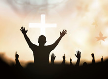 Praise And Worship Concept: Silhouette Human Raising Hands To Praying God On Blurred White Cross With Crown Of Thorn Sunset Background