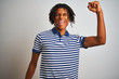 © Krakenimages.com - Afro man with dreadlocks wearing striped blue polo standing over isolated white background Dancing happy and cheerful, smiling moving casual and confident listening to music