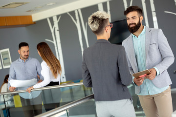 Business people discussing over documents in office lobby.