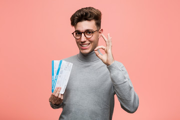 Wall Mural - Young cool man holding an air tickets cheerful and confident showing ok gesture.