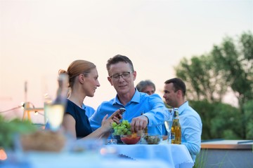 Canvas Print - Businesswoman using smartphone by businessman during rooftop party