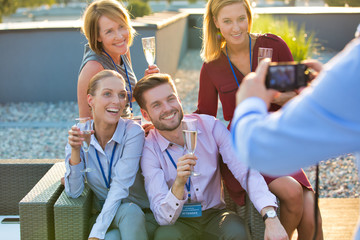 Canvas Print - Businessman photographing colleagues during rooftop success party