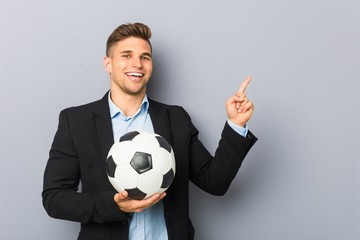 Wall Mural - Young soccer trainer smiling cheerfully pointing with forefinger away.