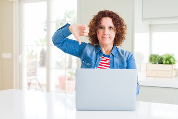 Sticker - Senior woman working using computer laptop with angry face, negative sign showing dislike with thumbs down, rejection concept