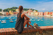 canvas print picture - Tourist woman in Sestri Levante, Liguria, Italy. Scenic fishing village with traditional houses and clear blue water. Summer vacation rich resort with picturesque harbour and nice sand beach
