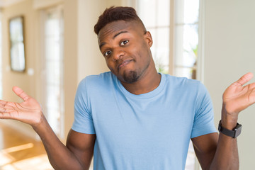 Sticker - Handsome african american man wearing casual t-shirt clueless and confused expression with arms and hands raised. Doubt concept.