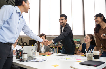 Wall Mural - Asian business people smart casual wear shaking hands while working in the creative office. Business team creative concept