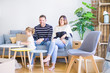 © Krakenimages.com - Beautiful family, parents sitting on the sofa drinking coffee looking his kid playing at new home around cardboard boxes