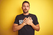 © Krakenimages.com - Young safeguard man wearing security uniform over yellow isolated background smiling with hands on chest with closed eyes and grateful gesture on face. Health concept.