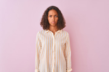 Canvas Print - Young brazilian woman wearing striped shirt standing over isolated pink background Relaxed with serious expression on face. Simple and natural looking at the camera.