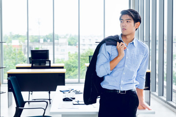 Wall Mural - Young Asian Businessperson is standing smart poses and smile at co working space decorated in modern office style for startup business students and freelancers