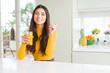 © Krakenimages.com - Young woman drinking a glass of fresh orange juice very happy pointing with hand and finger to the side