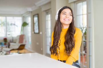 Sticker - Young woman wearing headphones listening to music looking away to side with smile on face, natural expression. Laughing confident.