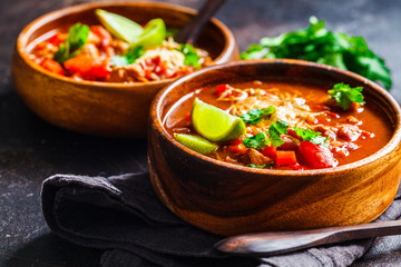 Wall Mural - Traditional mexican bean soup with meat and cheese in wooden bowl, dark background. Mexican food concept.