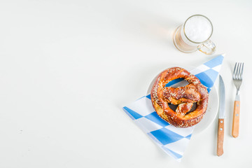 Wall Mural - Oktoberfest festive cutlery set  with with a traditional checkered  tablecloth, plate, pretzel, fork, knife and a glass of beer. background for Restoration menu