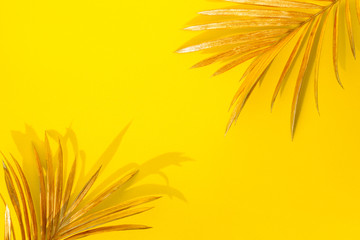 Wall Mural - Golden palm leaves on yellow background. Creative minimal modern concept of organic beauty trend.