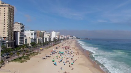 Wall Mural - Rio de Janeiro, Brazil, flyover shot of famous Ipanema Beach showing colourful sun umbrellas and waves breaking on the shore on a sunny day.