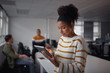 © StratfordProductions - Portrait of a young Brazilian businesswoman using tablet and her colleagues working together in the background in South America