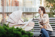 © Тарас Нагирняк - A beautiful young mother with a newborn baby in a stroller drinks tea in a street cafe and talking by her phone. Fashionable modern mom with a baby.