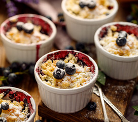 Wall Mural - Blueberry crumble, stewed bilberries topped with crumble of flour, butter and sugar  in a baking dishes on a wooden 