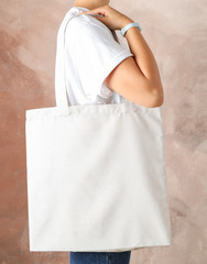 Wall Mural - Young woman holding tote bag against brown background, empty space