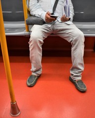 Passenger sitting during a subway ride using his smartphone