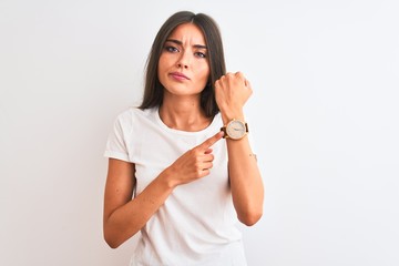 Sticker - Young beautiful woman wearing casual t-shirt standing over isolated white background In hurry pointing to watch time, impatience, looking at the camera with relaxed expression