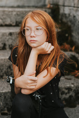 Very sad teenage girl sitting on stairs, looking away