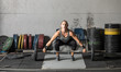 Young woman lifting heavy weights in grungy gym.