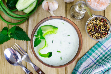 Traditional greek dip sauce or dressing tzatziki prepared with grated cucumber, yogurt, olive oil and fresh dill on wooden table in ceramic bowl.