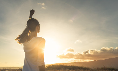 Young female outdoors with fist in the air feeling strong and confident. Victory and success concept. 